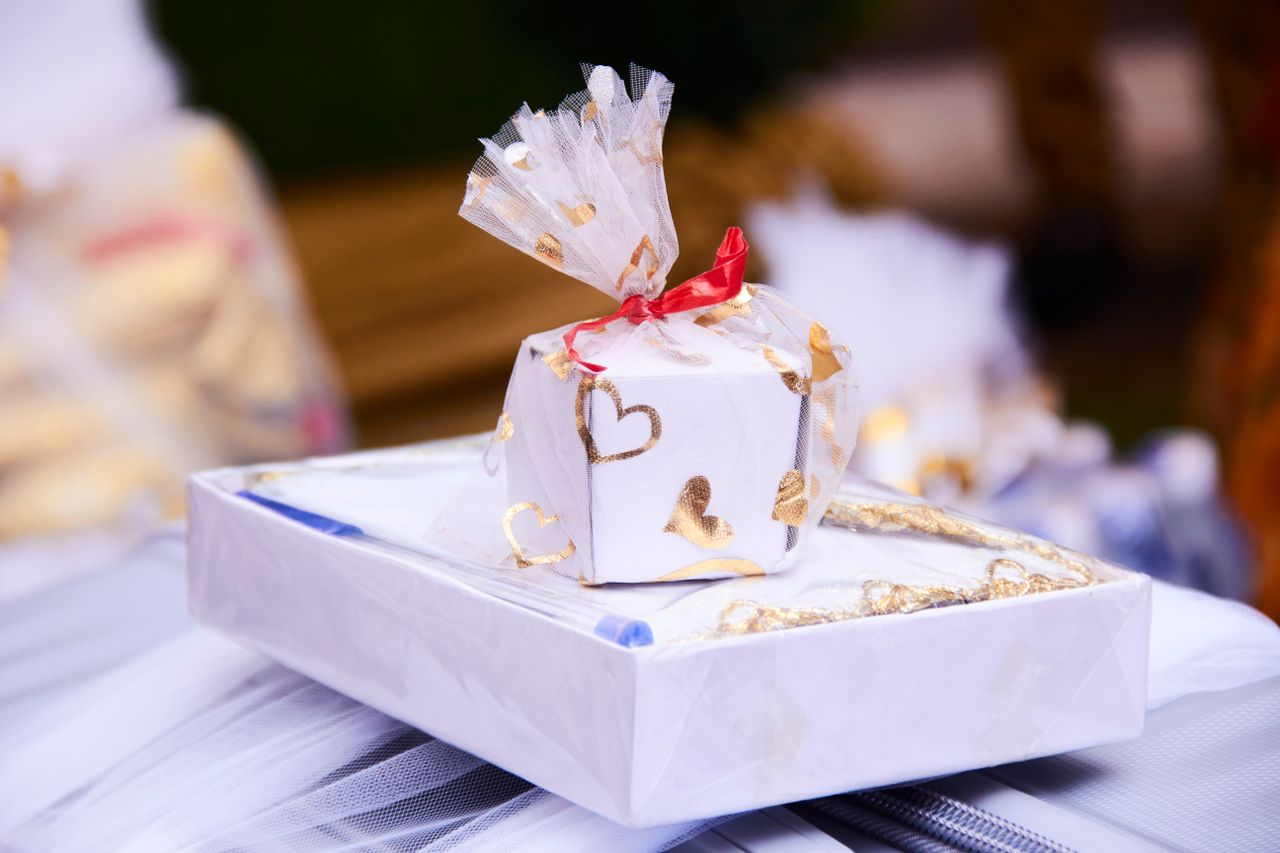 A beautifully wrapped gift box with golden hearts and red ribbon, perfect for romantic occasions.